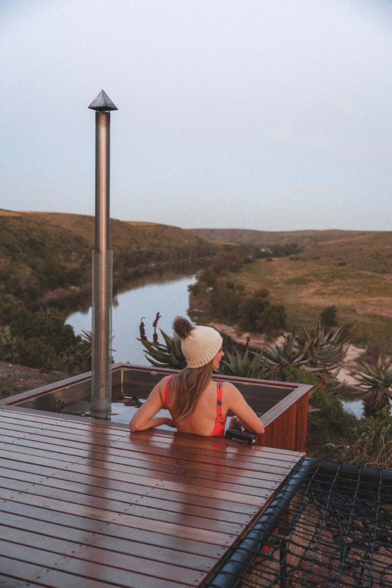 Young woman sitting in a hot tub overlooking a river