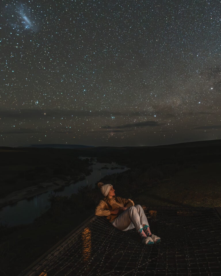 young woman lying on a cargo net under a starry sky